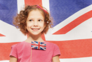 a young girl holding the United Kingdom flag, smiling, with the Union Jack as a background