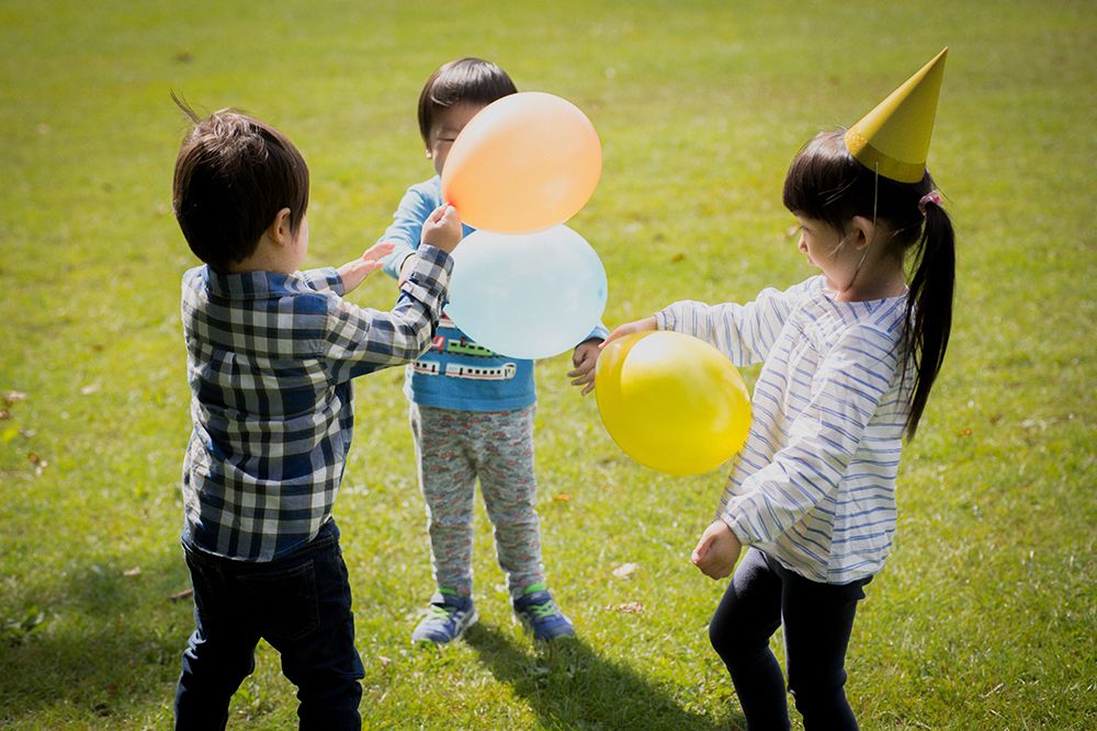 Three kids playing with balloons