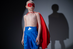 A bald boy dressed as a superhero